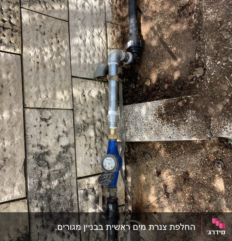 צינור מים עם מד לחץ ומחבר מתכת על רצפה